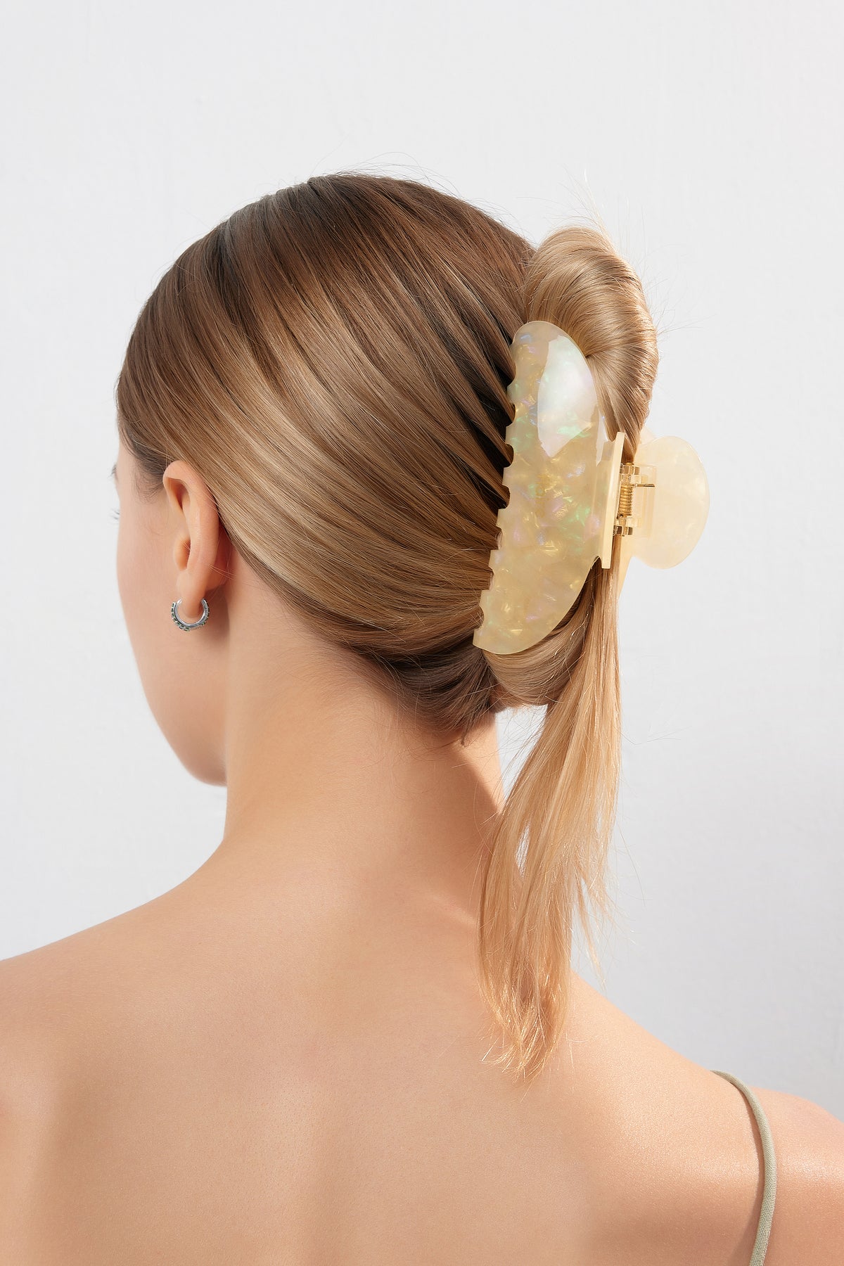 Person with light brown/blonde hair in a low twist, secured by an Amelia Butterfly Garden Claw Clip in Daisy, showcasing a pearlescent finish and sturdy grip.
